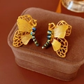 Vista macro de pendientes de mariposa dorados con cuentas de colores en estuche - Estilo de Mariposa de Dos Formas de Uso / Dorado-Púrpura
