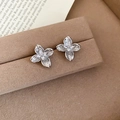 Macro view of silver clover flower stud earrings with zircon stones on brown velvet - Silver