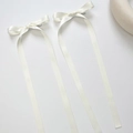 Detailed view of a pair of white satin bow hair clips with long ribbons in ballet style - Beige (1 Pair)