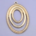 Detailopname van de gouden ovale hanger met gestructureerde concentrische ringen en oogje - Goud