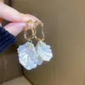 Gros plan de boucles d'oreilles pétales dorées tenues à la main pour un look élégant - Gland de pétale géométrique doré (11#)