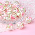 Close-up of clear acrylic beads with pink mushroom motifs in a glass dish with lace - Transparent Bead + Pink Green Mushroom / 18mm