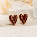 Dettaglio di orecchini a cuore rosso con bordo dorato su supporto decorativo bianco - Cuore Geometrico Rosso Vino