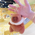 Cute brown plush capybara keychain with white collar and gold ring on blurred background - Donut Dark Brown + Gold Clip