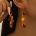 Close-up of layered orange maple leaf drop earrings worn by a model in autumn light - Earrings (01 KC Gold DZ-099)