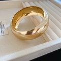 Nahaufnahme des breiten goldenen Armreifs mit polierter Oberfläche auf Schmuckkästchen - Klein / Gold