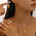 Macro detail of a minimalist gold rose jewelry set featuring a necklace, earrings, and ring - Rose Necklace, Earrings, Ring / Gold Rose 3-Piece Jewelry Set