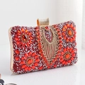 Dettaglio di motivi floreali in strass rossi e frange di cristallo su pochette da sera - Rosso