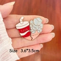 Detailed close-up of heart-shaped Love and Forever enamel pins held by hand - Coke and Ice Cube Pair