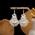 Macro shot of silver fan-shaped ethnic earrings with intricate hollow patterns and beads - Silver Phoenix