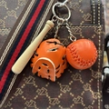 Detailed view of mini orange baseball glove and wooden bat keychain on a branded bag - 3.5CM Orange/Black Strap
