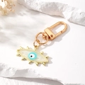 Detailaufnahme des goldenen Evil Eye Schlüsselanhängers mit blauem Emaille-Auge - White Burst Eye