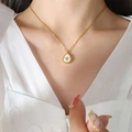 Detail of gold teardrop pendant with crown motif and white shell inlay on model - Crown Necklace / Gold