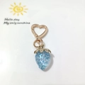 Close-up of a blue strawberry keychain with heart-shaped hook and golden metal finish - Heart Clasp-Light Blue Strawberry