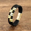 Dettaglio in pelle intrecciata nera multistrato con chiusura magnetica dorata su legno - Oro