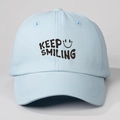 Detail shot of blue cotton baseball cap featuring Keep Smiling printed text and smiley face - One Size / Sky Blue
