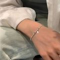 Zartes silbernes Perlenarmband mit blauen Akzentperlen und kleinem Fisch-Anhänger am Handgelenk - Silber und Blau Zweifarbig