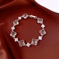 Close-up of silver-tone clover bracelet with faceted crystals on red silk background - Transparent Faceted Crystal (Clover) / Silver-White