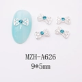 Macro detail of 9x5mm silver bow nail charms with blue rhinestones for art decoration - Silver Alloy Hollow Pattern Bow (A626)