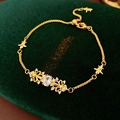 Detail of gold fleur-de-lis bracelet with white zircon on dark green velvet background - Gold