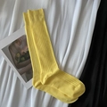Ribbed knit cotton long socks in bright yellow color laid flat on a stylish fabric background - Calf-length Lemon Yellow