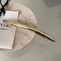 Minimalist curved metal hair clip in polished gold finish on marble tray - Bar Clip Gold