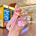 Pink unicorn quicksand keychain with acrylic heart-shaped charm and golden bell detail - Luminous Donut Heart Perfume Bottle