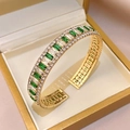 Detailed macro view of an emerald green gemstone bangle set in a luxury gold jewelry box - Bangle - Green Zircon - Rectangular