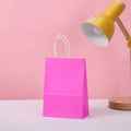 Detailed view of a rose pink kraft paper gift bag featuring white rope handles on a desk - 15*11*6 / Rose Red