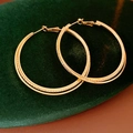 Close-up of golden interlocking hoop earrings with textured finish on green velvet - Gold (925 Sterling Silver Earring Post)