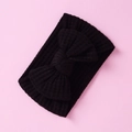 Detail of a black waffle-knit baby headband with a large bow on a pink background - Black-Bow