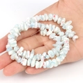 Hand holding irregular white shell beads with blue and red textures for DIY jewelry - Irregular Light Blue