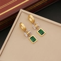 Golden hoop earrings with emerald square pendant and crystal bow on a leather jewelry box - Earrings / Gold/Green