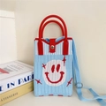 Detail of blue knitted mini bag with a red smiley face and adjustable shoulder strap - 20 Phone Bag-Blue Smiley