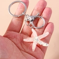 Detailed shot of a pink resin starfish keychain with iridescent sequins held by hand - Pink Starfish
