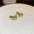 Gros plan de boucles d'oreilles en C à double rangée avec pierres vertes et zircons blancs - Boucles d'Oreilles en Diamant Vert et Blanc à Double Rangée d'Or