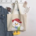 Close-up of cute cartoon white duck canvas tote bag with 3D plush yellow feet detail - Beige