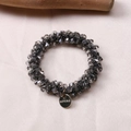 Detailed view of faceted grey crystal beads and golden metallic logo charm on silk - Dark Gray