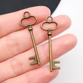 Vintage bronze alloy key pendant with heart bow shape held in hand for DIY jewelry - Antique Bronze Key 14x40mm