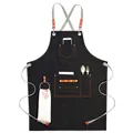Black denim work apron with gray cross-back straps and brown leather details - Black Denim with Ribbon Straps & Metal Loop
