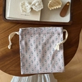 Close-up of a floral drawstring cotton pouch on a rustic wooden table with vintage decor - Grey Base Small Flowers