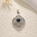 Detailed view of silver flower pendant featuring a dark gemstone and zircon embellishments - Flower