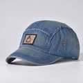 Detail van blauwe gewassen denim camper cap met metalen ringpatch en zijwaartse oogjes - Donker denim
