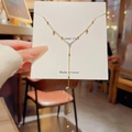 Elegante goldene Y-Halskette mit Quasten und kleinen Perlen auf einer Geschenkkarte - Gold