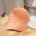 Detail of light orange cotton baseball cap on wooden surface with decorative flowers - Orange