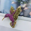 Detailed close-up of hummingbird brooch with purple and amber crystals on gold alloy - Antique Gold + Pink