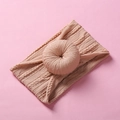 Close-up of pink soft nylon baby headband with a knitted donut bow on a matching background - Khaki
