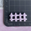 Size display of a small pink resin picket fence charm on a centimeter scale cutting mat - Purple Fence / Shiny Purple