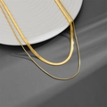 Collana a doppio strato in acciaio al titanio dorato su un piatto di ceramica - Collana Oro