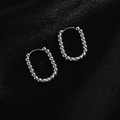 Vue détaillée des boucles d'oreilles perlées argentées sur fond de soie noire - Ovale Perlé / Acier